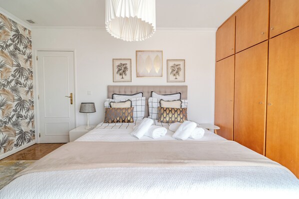 A neatly arranged bedroom with a bed, a wardrobe, and wall art. - MARIA HOME REALL`S (Real)