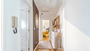 A hallway with a telephone, a mirror, a rug, and a wicker basket.