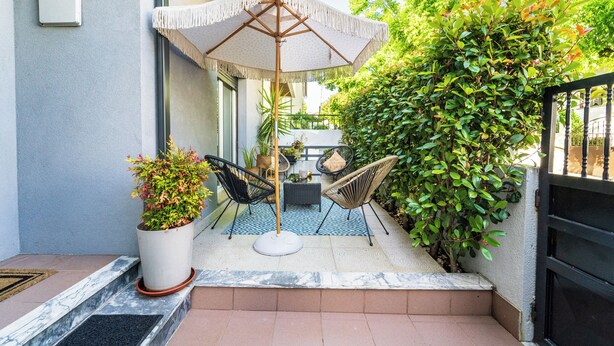 A patio with a table and chairs, a potted plant, and a large umbrella.
