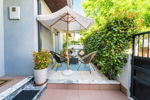 A patio with a table and chairs, a potted plant, and a large umbrella. - MARIA HOME REALL`S (Real)