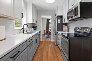 A modern kitchen with white cabinets, a stainless steel oven, and a microwave.