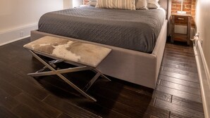 A bedroom with a bed, a modern ceiling fan, a brick wall, and a wooden floor. - Limited Offer: Cozy Condo by French Quarter (New Orleans)