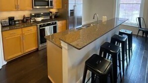 A modern kitchen with wooden cabinets, stainless steel appliances, and a granite countertop. - Limited Offer: Cozy Condo by French Quarter (New Orleans)