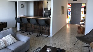 Un soggiorno moderno con un divano grigio, un tavolino da caffè e un'area bar con sgabelli.