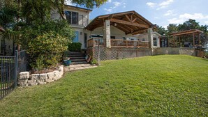 A two-story house with a covered patio and a stone retaining wall.