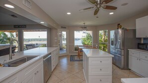 A modern kitchen with a large island, stainless steel appliances, and a view to the outside.