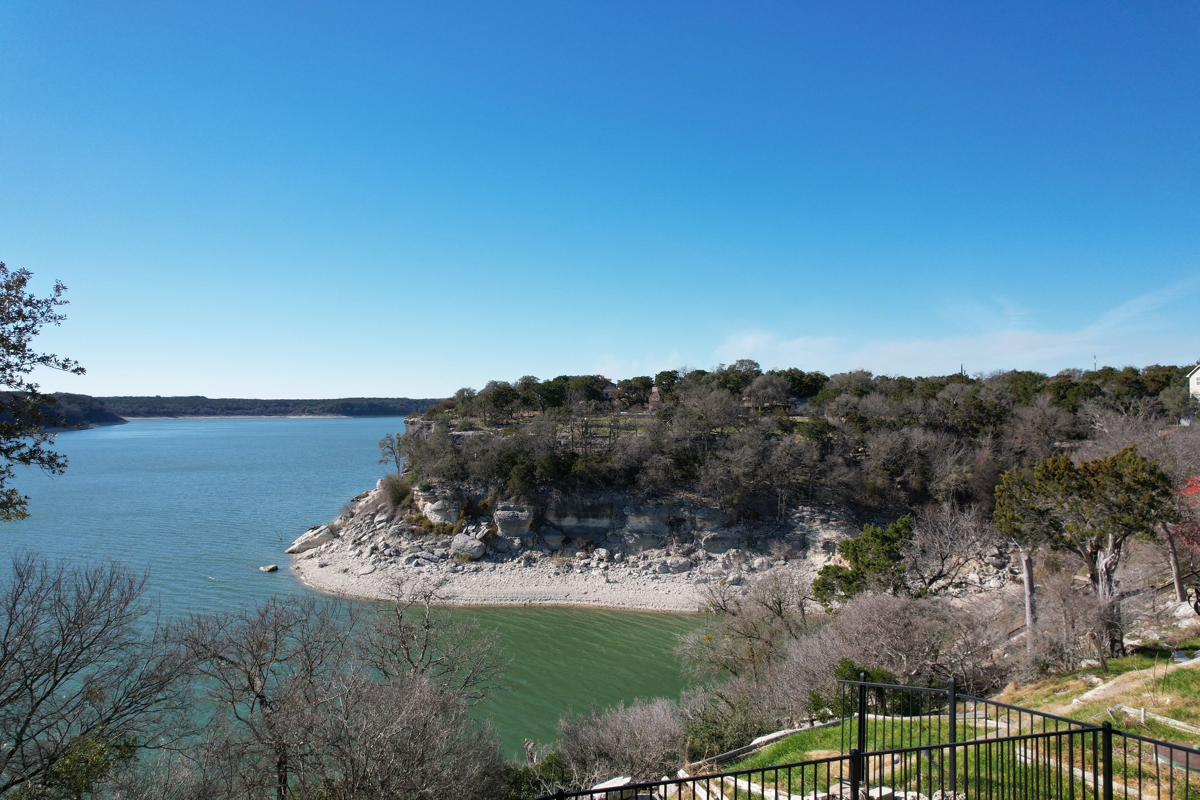 A coastal landscape with a clear view of the sea, a rocky shoreline, and a forested area.