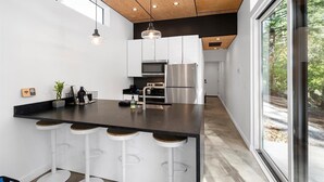 Una cucina moderna con isola centrale, sgabelli da bar, forno a incasso e frigorifero in acciaio inossidabile.
