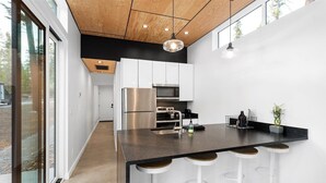 A modern kitchen with a central island, stainless steel appliances, and a black countertop.