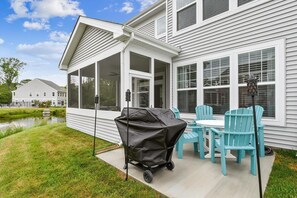 Eine überdachte Terrasse im Freien mit Grill, Stühlen und Tisch.