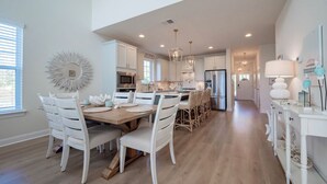Una cocina amplia con armarios blancos, una isla central e iluminación moderna.