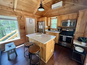 Cocina de cabaña de madera con una isla central, taburetes de bar, un refrigerador, una estufa y un microondas.