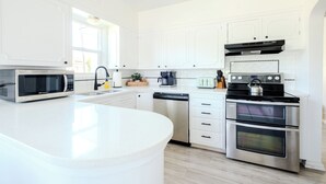 A modern kitchen with white cabinetry, stainless steel appliances, and a central island. - The Cache Cottage ~ 5 BDR, 2.5 Bath SAUNA USU Logan Canyon SKITHEBEAV Bear Lake (Logan)