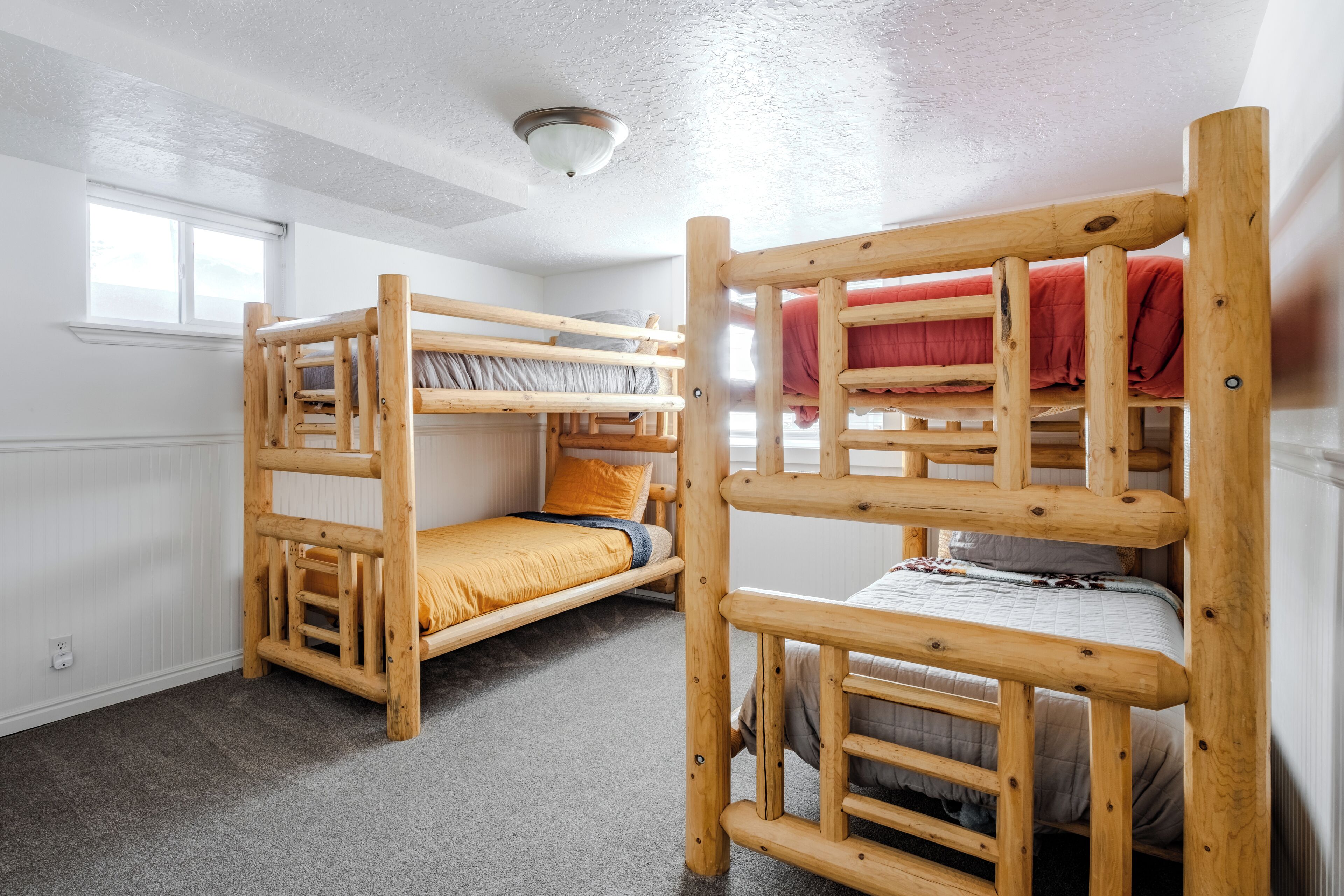 A room with two bunk beds, a window, and a ceiling light.