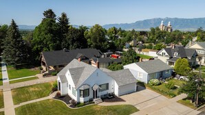 A residential area with houses, a prominent mountain range in the background, and a lighthouse structure. - The Cache Cottage ~ 5 BDR, 2.5 Bath SAUNA USU Logan Canyon SKITHEBEAV Bear Lake (Logan)