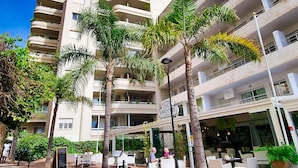 A multi-story hotel with balconies, outdoor seating, and palm trees. - Magnificent One Bedroom Apartment in Marbella Center. (Marbella)