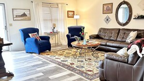 A living room with a brown leather sofa, two blue armchairs, a coffee table, and a patterned rug. - 🏡 Cozy Home <5 Miles to Boat Ramp—Book Now! (Scottsboro)