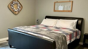 A bedroom with a bed, a ceiling fan, a 'Welcome' sign, a woven basket, and a small table. - 🏡 Cozy Home <5 Miles to Boat Ramp—Book Now! (Scottsboro)