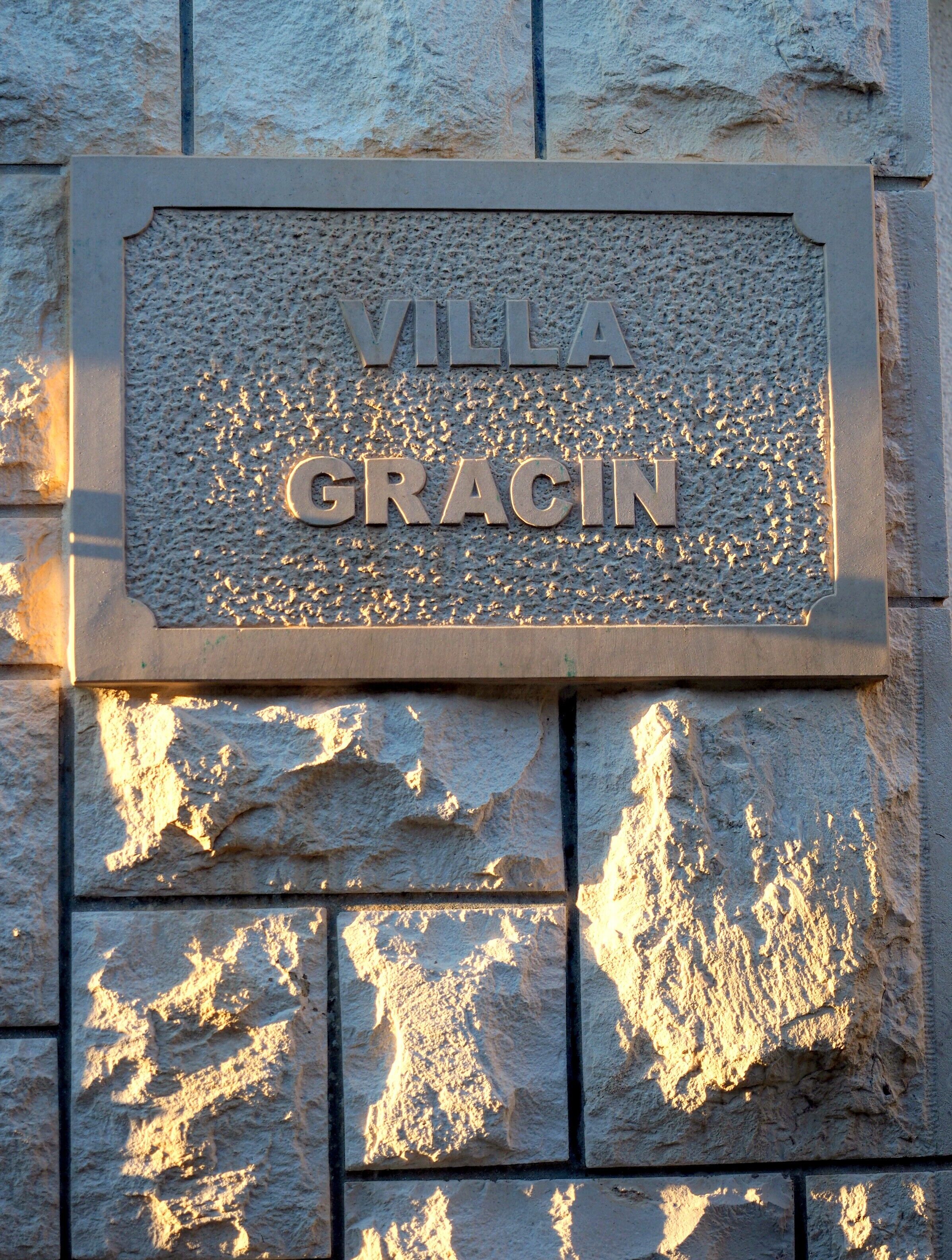 A sign with the text "VILLA GRACIN" on a textured stone wall.