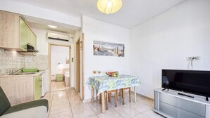 A compact living space with a kitchenette, dining area, and a TV.