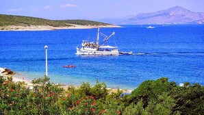 A boat on a clear blue sea with a mountainous backdrop.