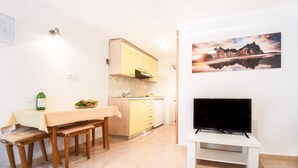 Eine kompakte Küche mit Essbereich, einem Fernseher und einem Bild an der Wand.
