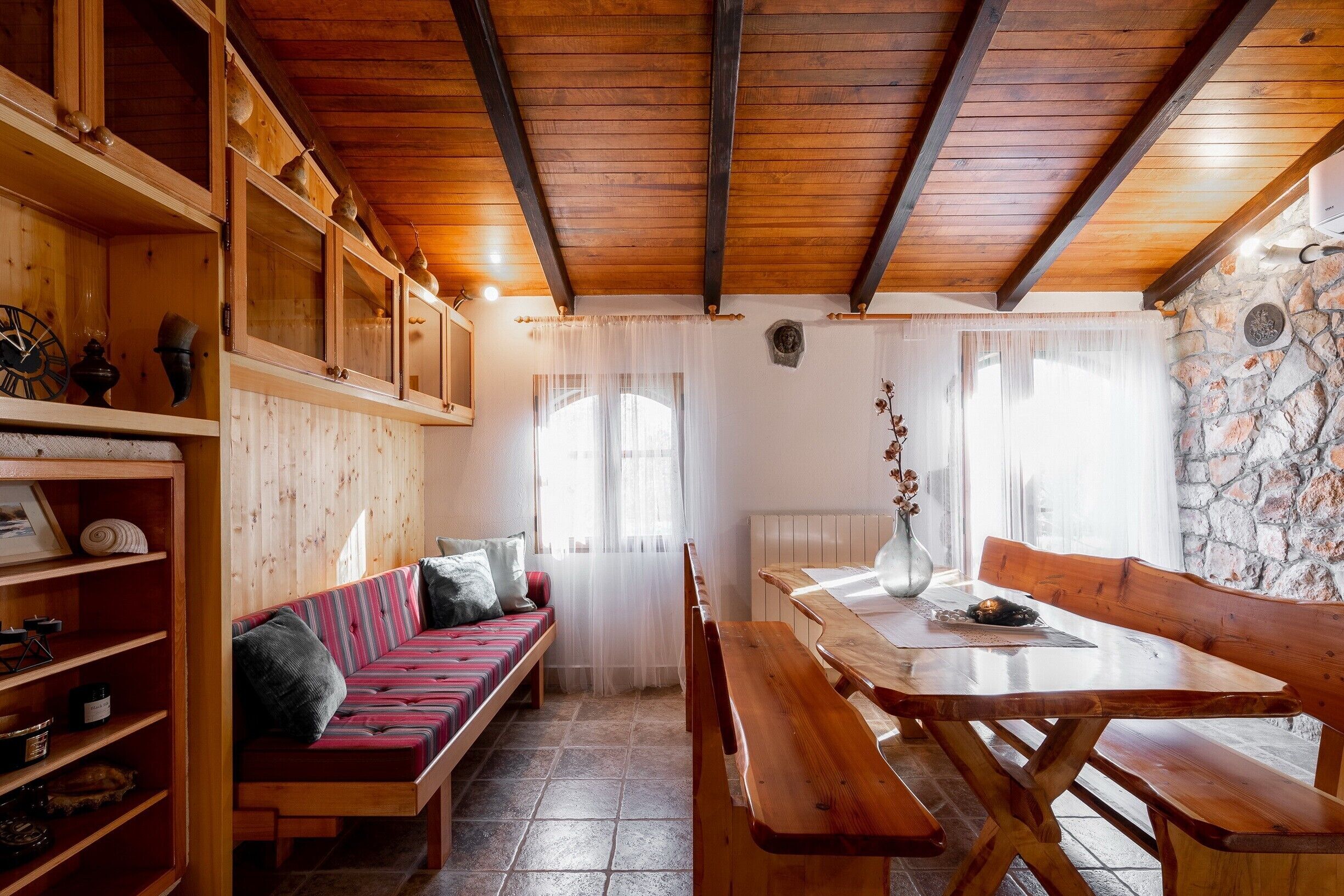 Una habitación acogedora con un banco de madera, una mesa y estanterías con diversos objetos.