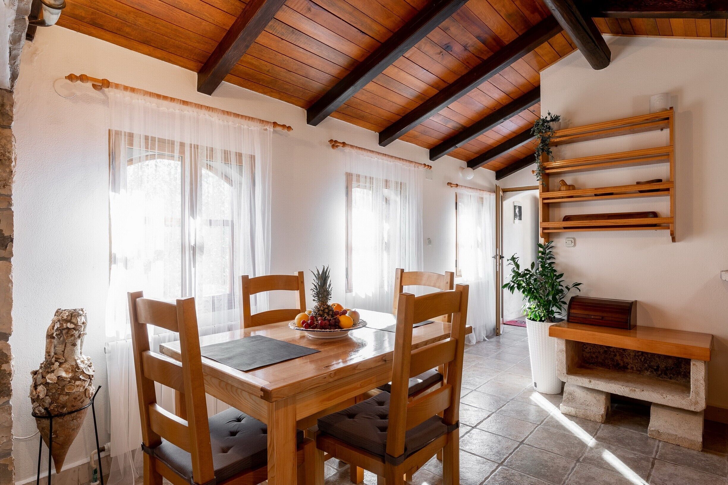 A wooden dining table with chairs, a fruit bowl, and a potted plant.