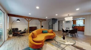 Relax in this stylish living space with a curved sofa, glass coffee table, and dining area.