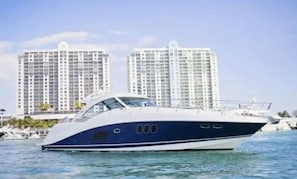 A yacht on water with high-rise buildings in the background.