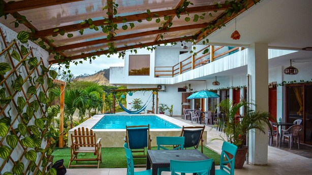 Un área de piscina con hamaca, mobiliario exterior y vistas a una montaña.