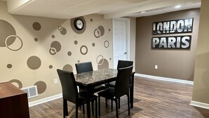 A dining area with a marble table and black chairs, a wall clock, and a sign reading "LONDON PARIS". - Charming Football Hall of Fame Bungalow (Canton)