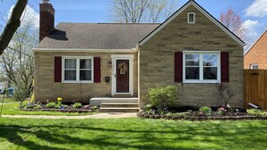 A two-story house with a brick chimney, a front porch, and a well-maintained lawn. - Charming Football Hall of Fame Bungalow (Canton)