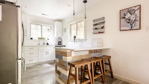 A modern kitchen with a wooden island, bar stools, and pendant lighting.