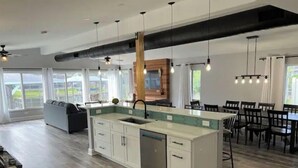 Una cocina moderna con una isla central, armarios blancos y un amplio ventanal con vistas al exterior.