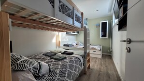 A compact bedroom with a bunk bed, a bedside table, a small wardrobe, and a TV mounted on the wall. - Utopia T2 32 M² fully equipped (Lanester)