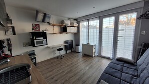 A compact kitchen with a microwave, a small dining table, and a sofa. - Utopia T2 32 M² fully equipped (Lanester)