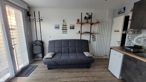 A compact living space with a sofa, kitchenette, and a radiator. - Utopia T2 32 M² fully equipped (Lanester)