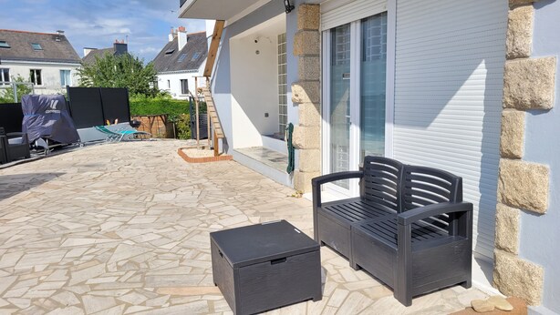 A patio with stone flooring, a black bench, and a storage box. - Utopia T2 32 M² fully equipped (Lanester)