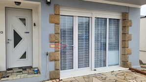 A house with a white door, a garage door, and a stone wall. - Utopia T2 32 M² fully equipped (Lanester)