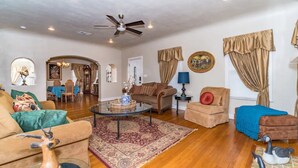 A spacious living room with a ceiling fan, a coffee table, and a variety of seating options including a sofa, armchairs, and a loveseat. - 3 BR, 2 Baths, Pets & family friendly, Historical safe home + 5 miles downtown (San Antonio)