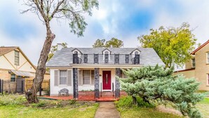 A two-story house with a red door, a small porch, and a tree in the front yard. - 3 BR, 2 Baths, Pets & family friendly, Historical safe home + 5 miles downtown (San Antonio)