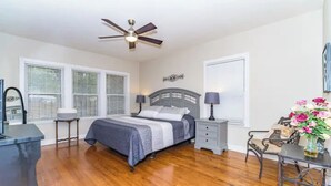 A bedroom with a bed, bedside tables, a desk, a chair, a ceiling fan, and a window with blinds. - 3 BR, 2 Baths, Pets & family friendly, Historical safe home + 5 miles downtown (San Antonio)