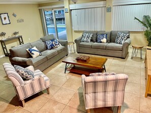 A living room with two sofas, a coffee table, and a striped armchair.