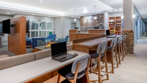Een moderne hotel lobby met een receptiebalie, een zithoek en een kitchenette.
