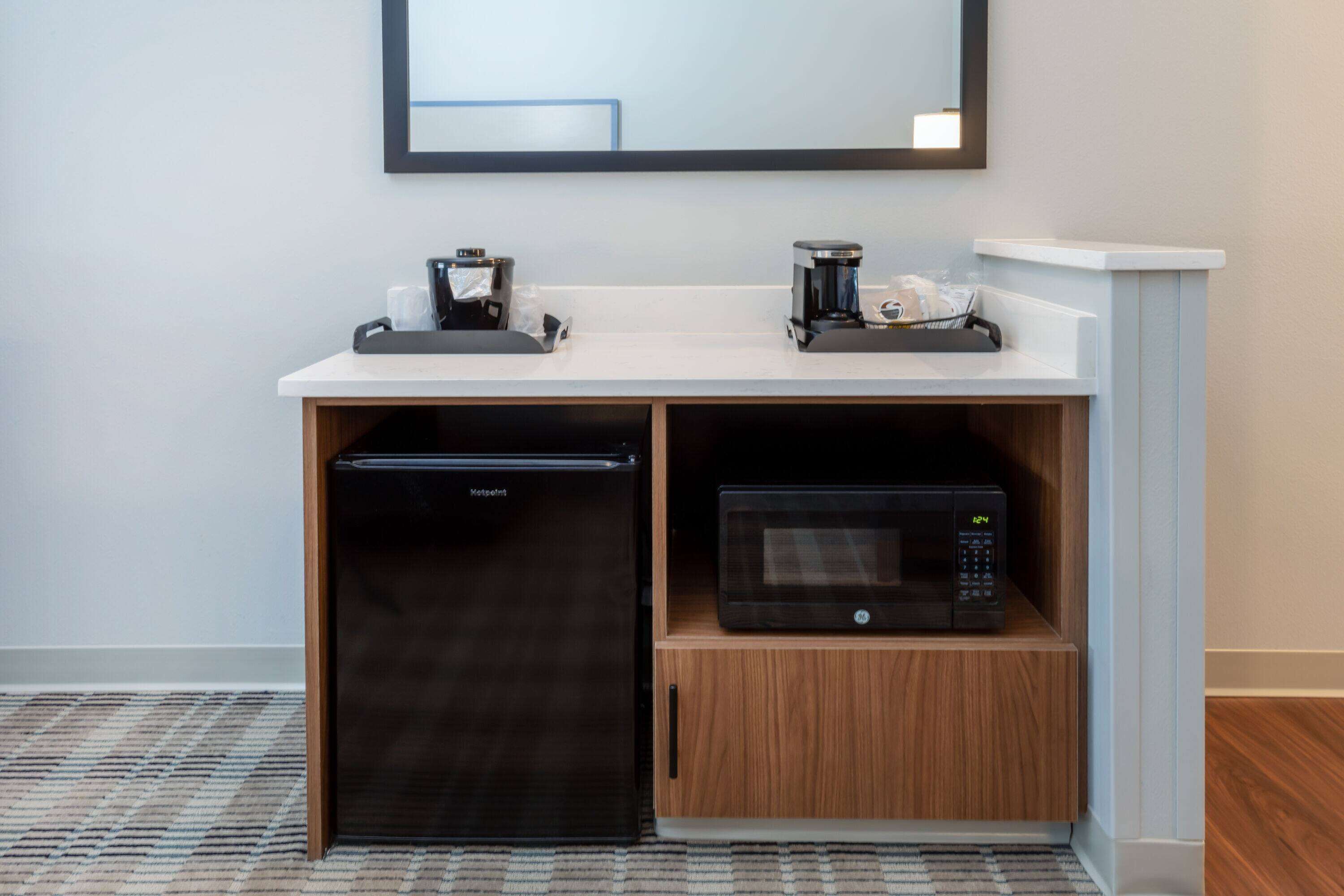 Una kitchenette equipada con refrigerador, microondas y cafetera.
