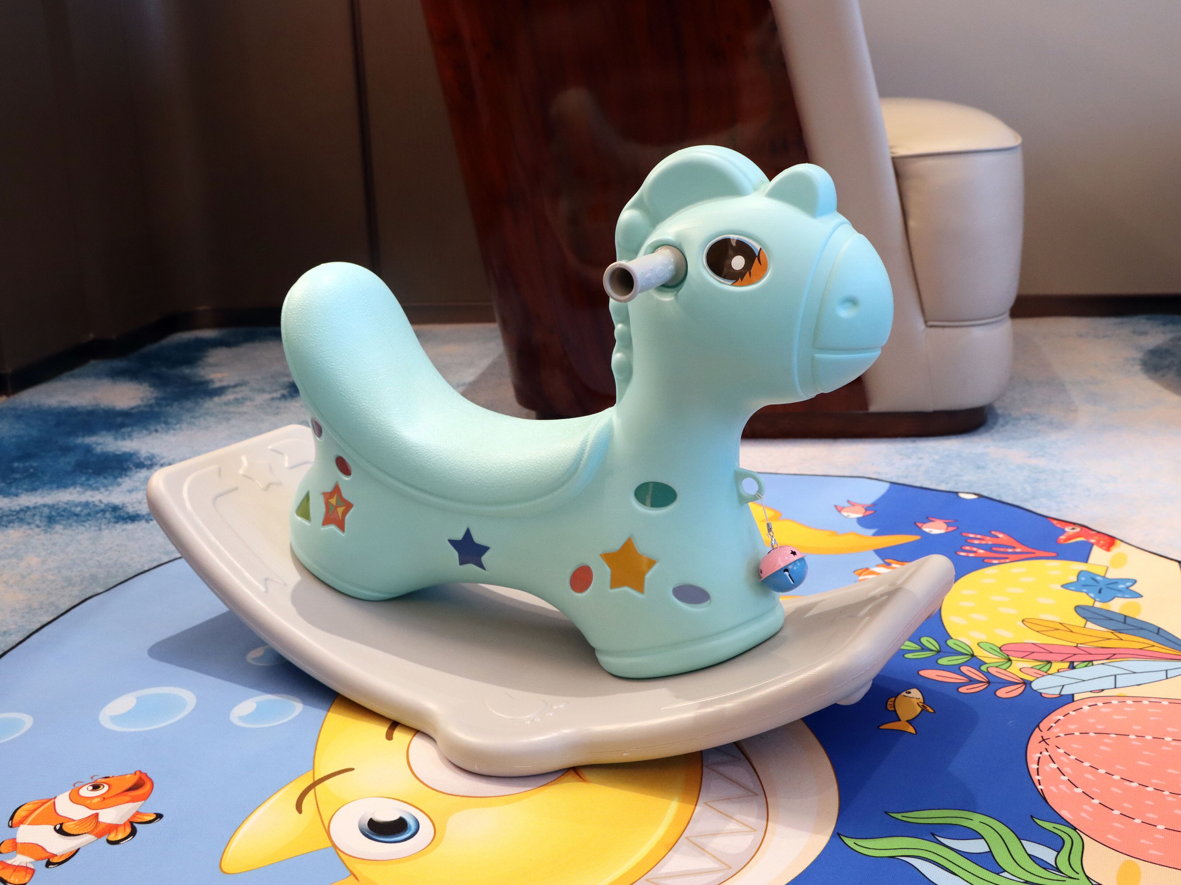 A toy giraffe on a colorful mat with a fish design.