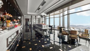 A modern hotel lobby with a marble floor, a long counter with food and drink options, and large windows offering a city view. - Wyndham Grand Zaozhuang (Zaozhuang)