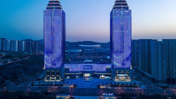 A modern building with two tall towers, a central entrance, and surrounding high-rise buildings. - Wyndham Grand Zaozhuang (Zaozhuang)
