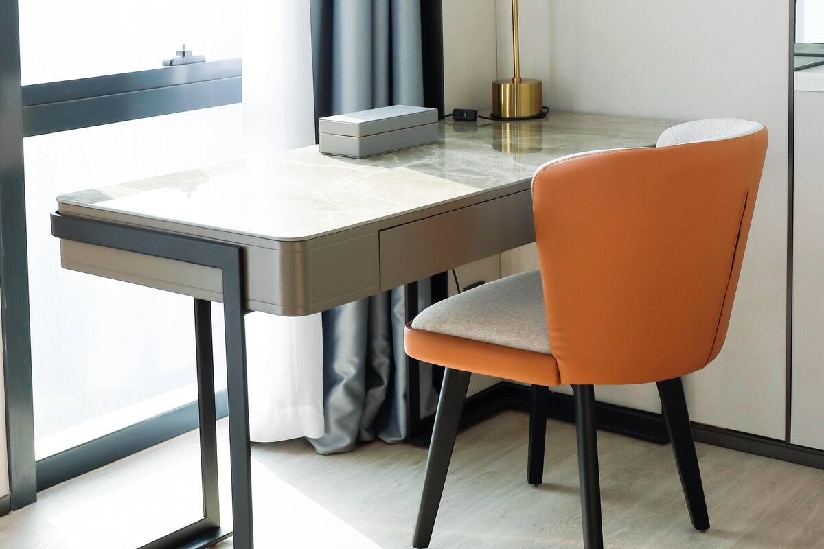 A modern room with a desk, chair, lamp, and curtains.